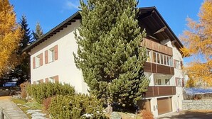 A two-story building with a sloped roof, a stone pathway, and a snow-covered ground. - Chesa Suot Rövens by Interhome (Samedan)