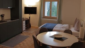 Pieni huone, jossa on pieni keittiö, ruokailutila, sänky ja televisio.
