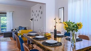 A dining area with a wooden table set for four, surrounded by chairs. There is a vase with sunflowers on the table, and a modern lamp in the background. - Komfortable, ruhige Erdgeschoss-Ferienwohnung by Interhome (Barban)