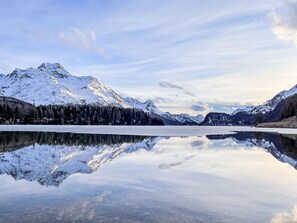 Un paysage de montagne paisible, avec un lac aux eaux limpides qui reflète les sommets et le ciel.
