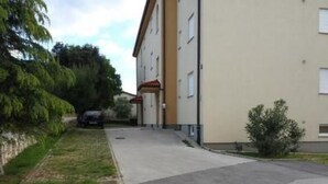A building with a flat roof, a visible entrance, and a paved driveway. - Appartement in Banjole mit Garten und Grill by Interhome (Pula/Banjole)