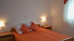 A bedroom with a bed, two bedside tables, and a wall-mounted light fixture. - Appartement in Banjole mit Garten und Grill by Interhome (Pula/Banjole)
