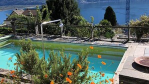 Ein Pool mit Blick auf eine Berglandschaft, umgeben von viel Grün und blauem Himmel.