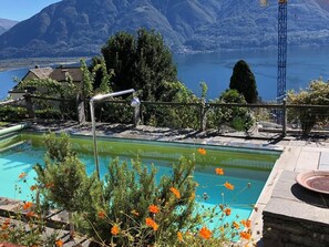 Ein Pool mit Blick auf eine Berglandschaft, umgeben von viel Grün und blauem Himmel.