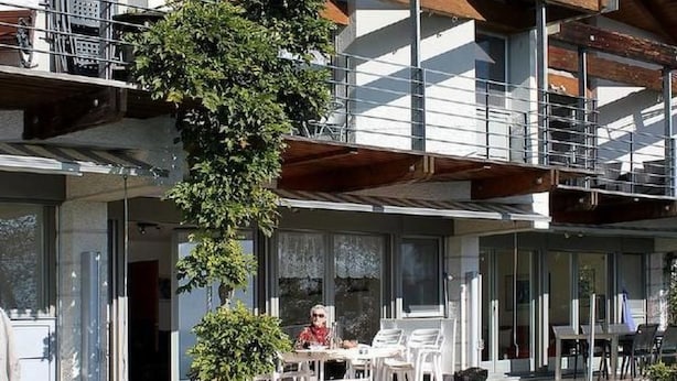 Un edificio de varios pisos con un área de estar al aire libre cubierta, un balcón y un césped bien cuidado.