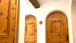 Un couloir avec des portes en bois et un motif décoratif en forme de soleil sur le mur.