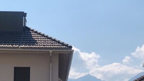 A residential building with a garage, a clear view of the sea, and a mountain in the background. - What a view by Interhome (Orselina)
