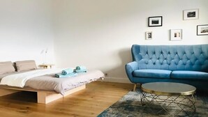 A bedroom with a bed, a blue sofa, a round coffee table, and a rug. - What a view by Interhome (Orselina)