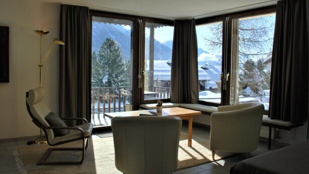 Ein modernes Hotelzimmer mit Balkon, einer Couch, einem Sessel und einem Tisch.