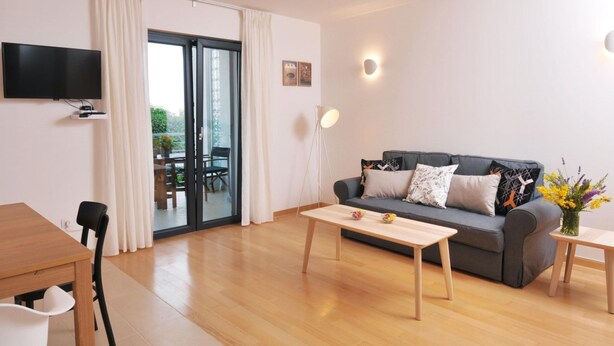 A modern living room with a sofa, coffee table, and a TV mounted on the wall. - Wohnung mit Blick auf das Wasser by Interhome (Medulin/Ližnjan)