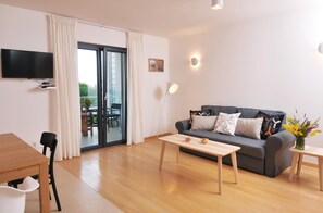 Ein modernes Wohnzimmer mit einer Couch, einem Couchtisch und einem an der Wand befestigten Fernseher.