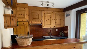 Una cocina con armarios de madera, encimera negra y ventana con vistas.