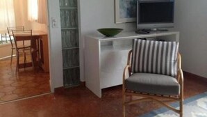A room with a white desk, a television, a striped chair, and a green bowl. - Studio Cresta Bianca by Interhome (Ronco sopra Ascona)