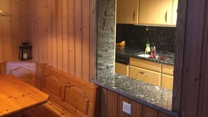 A wooden interior with a stone wall, wooden cabinets, and a granite countertop. - Chalet am Bühl by Interhome (Grindelwald)
