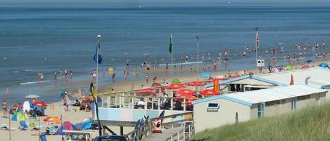 Une zone aménagée au bord de la plage, avec un parking, des vélos et des parasols de plage.