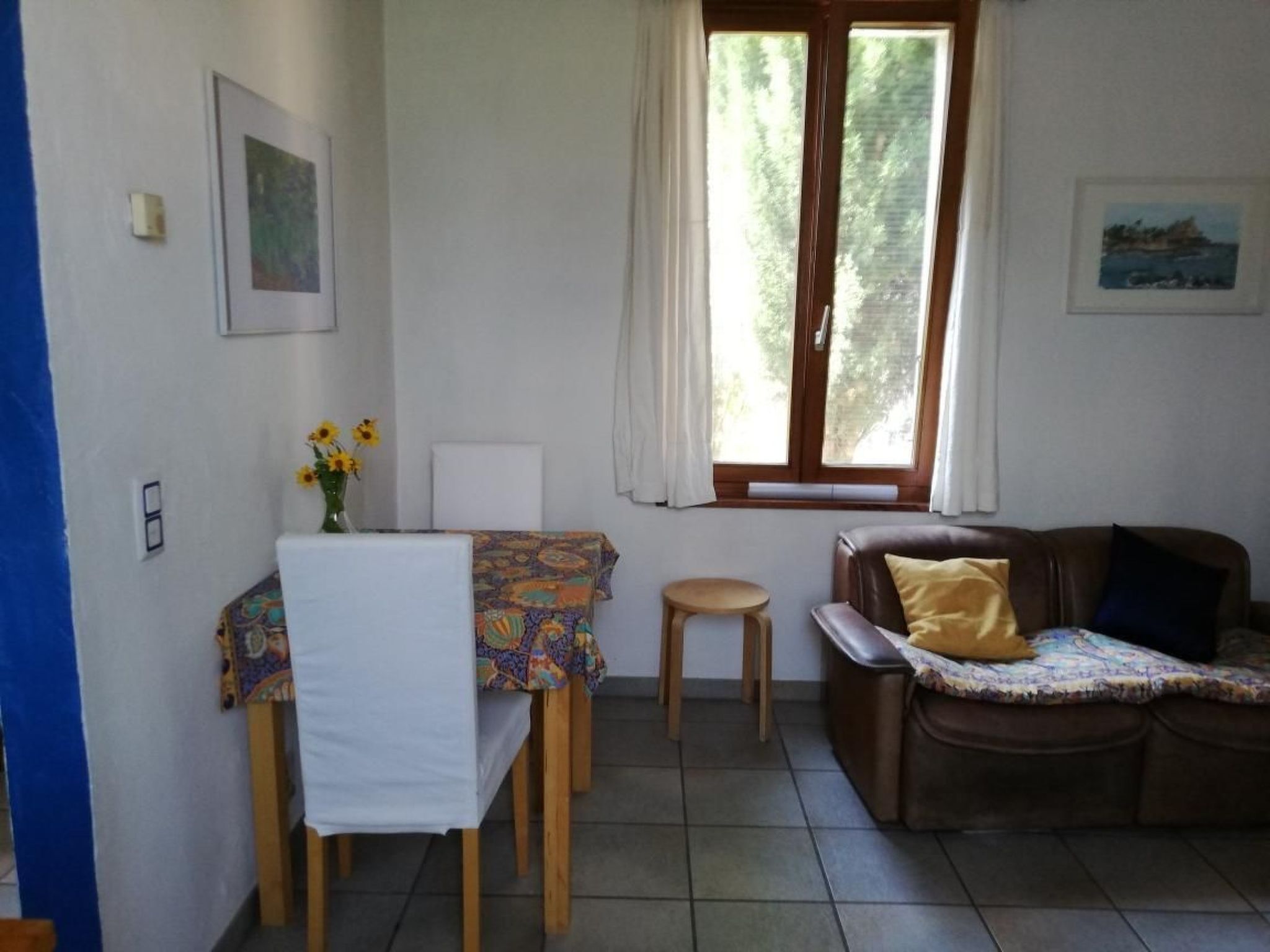Ein Zimmer mit Esstisch, Sofa und einem fensterbepflanzten Fenster.