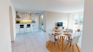 A modern kitchen with white cabinets, a central island, and a dining area with a round table and chairs. - Casa delle Vigne by Interhome (Minusio)