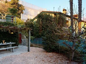 Een binnenplaats met een pergola, een stenen bank en een gebouw met een groen dak.