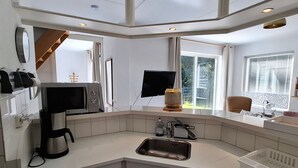 Une cuisine moderne équipée d’un évier d’angle, d’un four à micro-ondes, d’une machine à café et d’une fenêtre donnant sur l’extérieur.