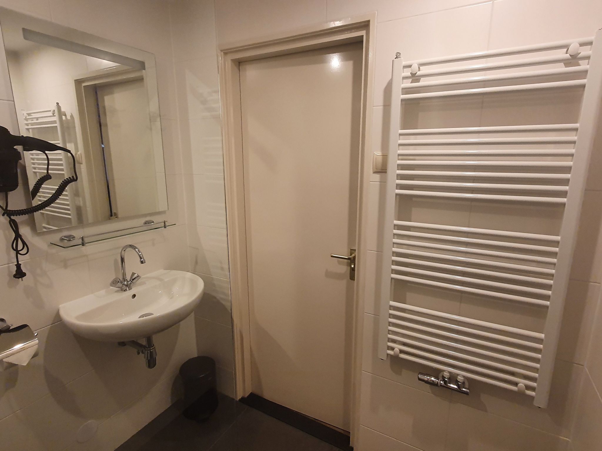 A bathroom with a sink, mirror, towel rack, and a door.
