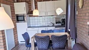 A modern kitchen with white cabinets, a microwave, and a hanging pot rack. - De Blenck 66 by Interhome (Callantsoog)