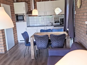 A modern kitchen with white cabinets, a microwave, and a hanging pot rack. - De Blenck 66 by Interhome (Callantsoog)