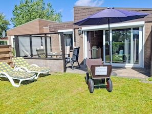 A modern outdoor area with a patio, lounge chairs, a table, and a wheelbarrow. - De Blenck 66 by Interhome (Callantsoog)