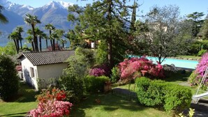 En have med swimmingpool, frodig vegetation og et bjerg i baggrunden.