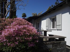 Un edificio blanco con un banco de piedra y una silla afuera.