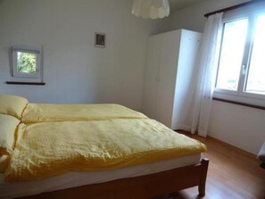 Ein Schlafzimmer mit einem Bett, einem Kleiderschrank, einem Fenster und einem kleinen Bild an der Wand.