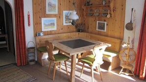 Un rincón comedor acogedor con una mesa y sillas de madera, un banco y una lámpara colgante.