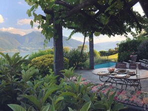 A poolside dining area with a view of mountains and a lake. - Casa Nespole, Familiennest mit Seesicht by Interhome (Minusio)