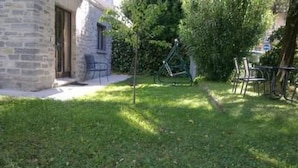 Ein Steinhaus mit kleiner Terrasse und Sitzbereich im Freien.