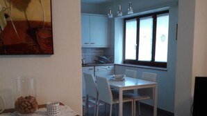 Ein Essbereich mit Tisch und Stühlen, im Hintergrund eine Küche und ein Bild an der Wand.