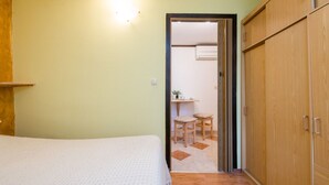 Un dormitorio con cama, armario y una pequeña mesa con sillas.