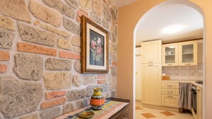 Una cocina con paredes de piedra, armarios de madera y suelo de baldosas.