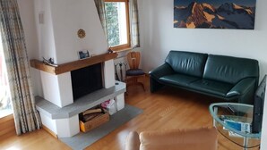Ein gemütliches Wohnzimmer mit Kamin, einem grünen Sofa und einem Glastisch.