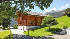 Un chalet en bois doté d’un toit à pente, de fondations en pierre et d’une allée pavée menant à une entrée blanche.