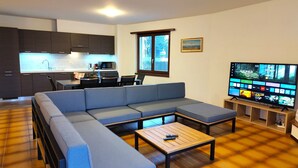 Een moderne woonkamer met een hoekbank, een salontafel en een flatscreen televisie.