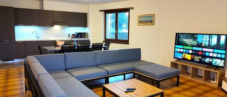 Una sala de estar moderna con un sofá modular, una mesa de centro y un televisor de pantalla plana.