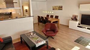 Un soggiorno moderno con zona pranzo, cucina e televisore.