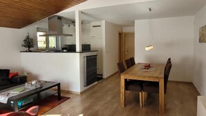 Un soggiorno moderno con angolo pranzo, cucina e una zona salotto accogliente con tavolino e poltrone.