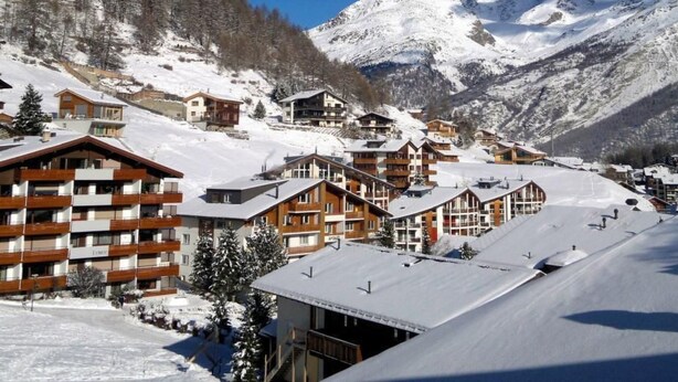 Un paese montano innevato con edifici in legno e una pista da sci.