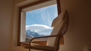 Une pièce avec une grande fenêtre, un plancher en bois et une seule chaise.