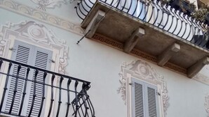 Ein Gebäude mit aufwendigen architektonischen Details, darunter dekorative Stuckarbeiten und ein Balkon mit schmiedeeisernem Geländer.