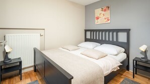 Una camera da letto con un letto, due comodini, un termosifone e un quadro appeso al muro.