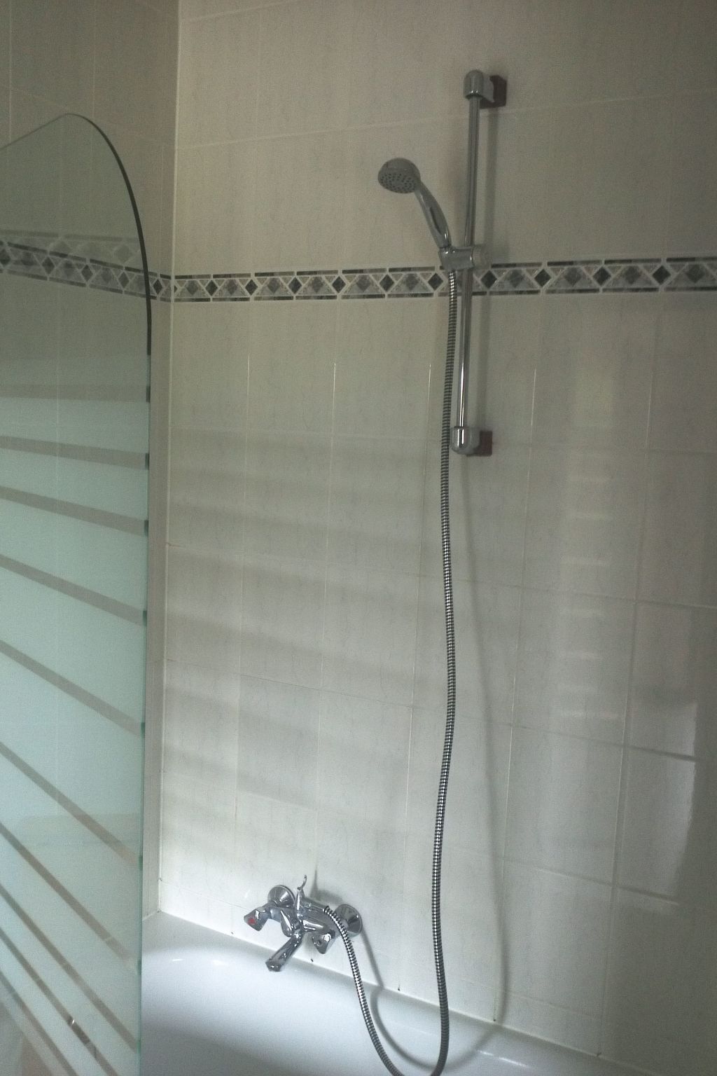 Une salle de bain dotée d’une douche à parois de verre, d’un pommeau de douche à main et d’un robinet mural.