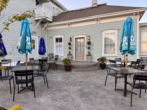 Un patio con mobiliario exterior, una pequeña escalera y una casa de color azul claro.