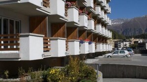Una hilera de edificios modernos de varios pisos con balcones, algunos con barandillas de madera y jardineras.