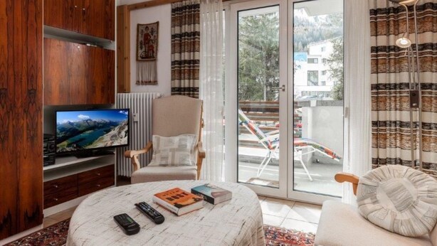 Una sala de estar moderna con televisor, sofá, sillón y una mesa de centro.